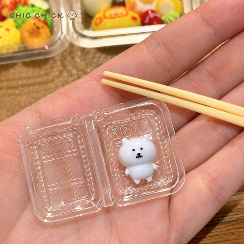 Hand holding the open clear box with the white bear squishy